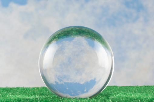 A crystal ball on grass before a blue sky