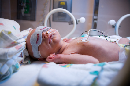 Premature in incubator with eyes covered