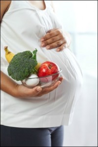 Pregnant woman holding healthy food near her belly