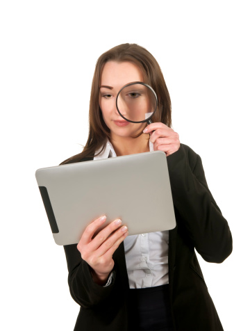 Woman examines tablet computer with magnifying glass