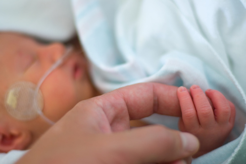 Sleeping infant holding adult finger