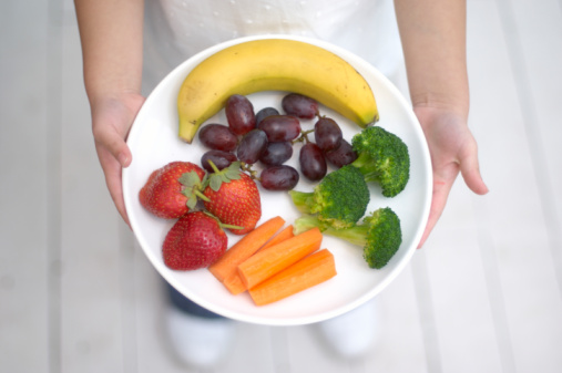 Hands holding healthy snacks on a plate
