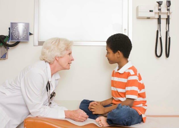 Doctor talks with a boy seated on examination table