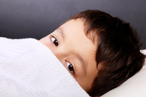 Little boy's eyes look out over blanket