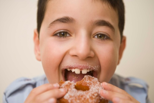 Boy taking bite of sugary doughnut