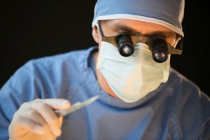 Surgeon Wearing Mask And Magnifying Glasses Holding Scalpel