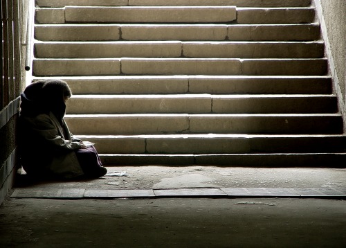 Homeless person sitting at base of steps