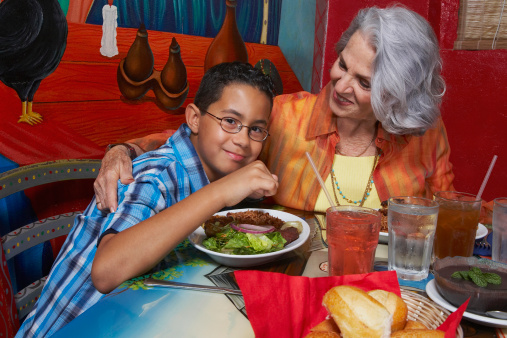 Close-up of a Latino boy with his grandmother eating dinner