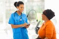 African medical nurse talking to a senior patient
