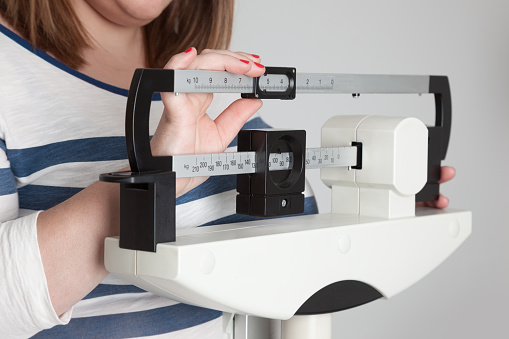 Overweight woman adjusts medical scale