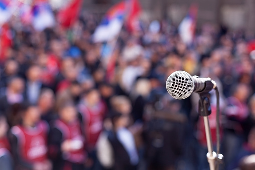 Image of a microphone in front of large crowd