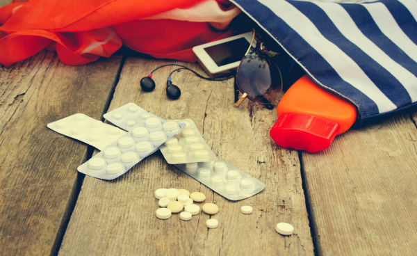 Stripped travel bag on ground with pills resting just outside of it