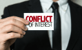 image of hand holding card with words "conflict of interest"