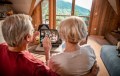 Back of heads of older couple looking at laptop with images of family waving back at them